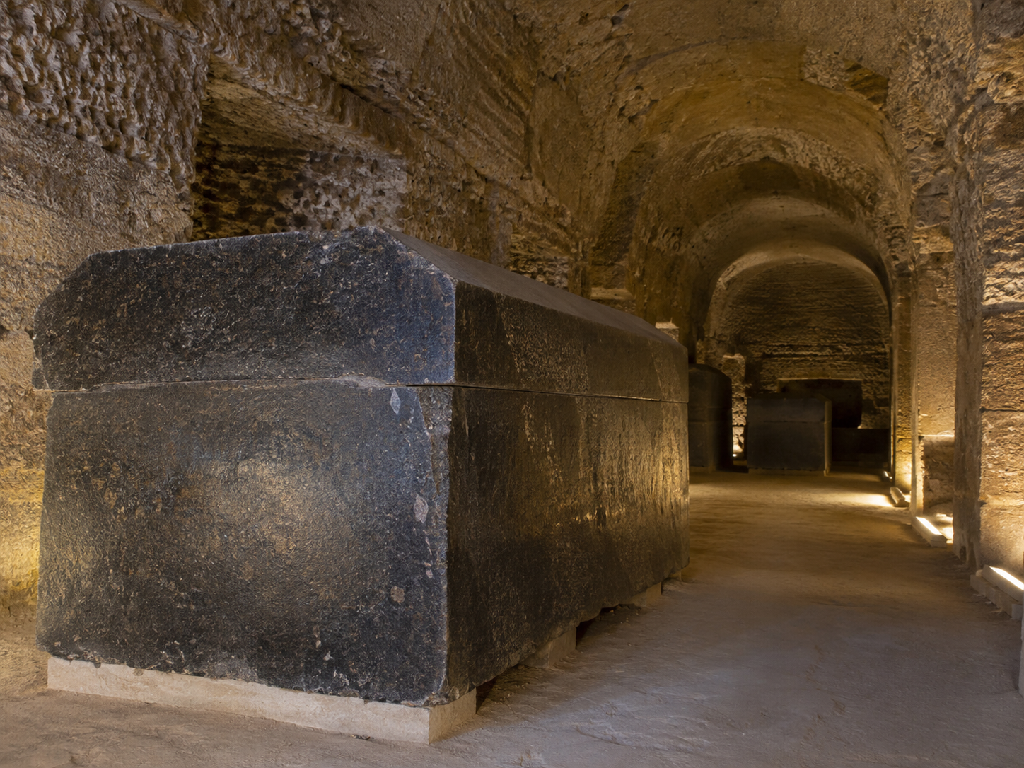 AI-generated illustrative reconstruction of a close-up view of a monumental granite sarcophagus and its lid inside the Serapeum.