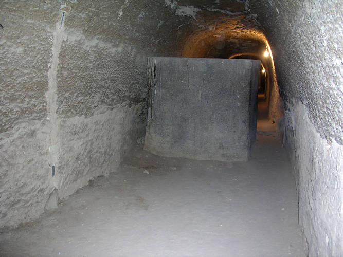 Photograph of an abandoned granite sarcophagus standing in a bare stone side-chamber of the Serapeum of Saqqara.
